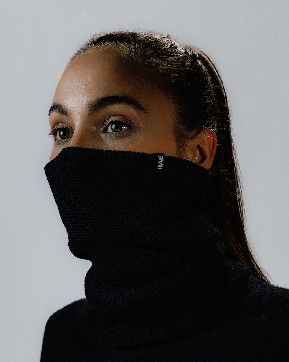 Das weibliche Model präsentiert den Neckwarmer in Schwarz