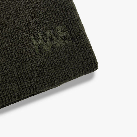 Nahaufnahme der Ton-in-Ton gestickten HAE Logo-Stickerei auf dem Guide Beanie in Grün (Olive) – Detailansicht der Acryl-Strickstruktur