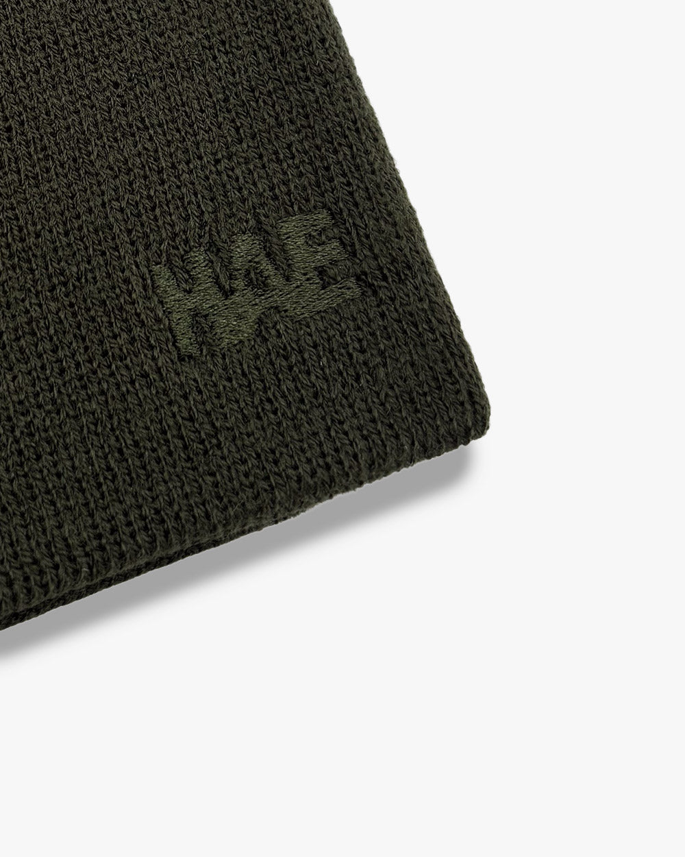 Nahaufnahme der Ton-in-Ton gestickten HAE Logo-Stickerei auf dem Guide Beanie in Grün (Olive) – Detailansicht der Acryl-Strickstruktur