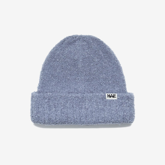 HAE Nomad Beanie in Blau, weiches meliertes Strickmuster mit HAE-Logo-Label, 23% Wolle 59% Acryl 17% Polyamid 1% Elastan, freigestellt vor weissem Hintergrund