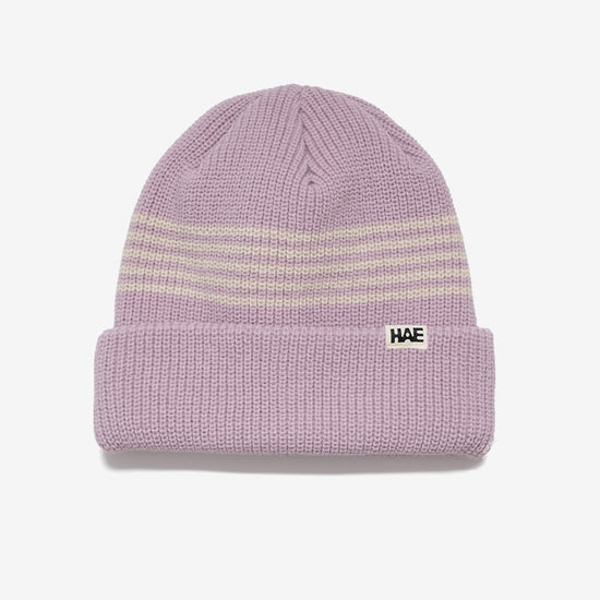 HAE Pathfinder Beanie in Lila mit beigen Ringelstreifen am Bund, HAE-Label, 100% Acryl, freigestellt vor weissem Hintergrund