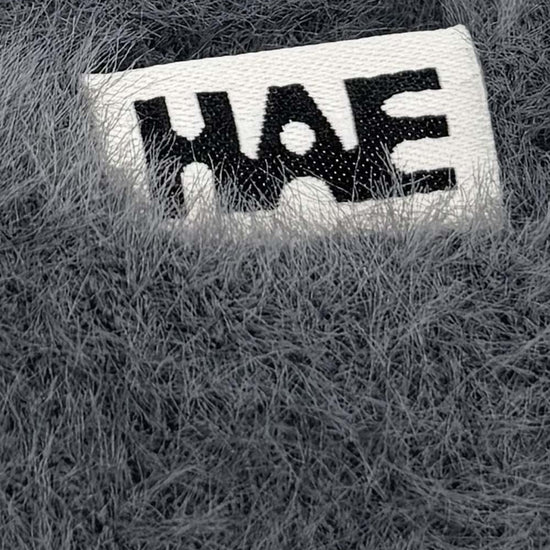 Adventurer 2.0 Mütze von HAE in Dunkelgrau – Detailaufnahme des HAE-Labels auf dem flauschigen Polyamid-Gewebe