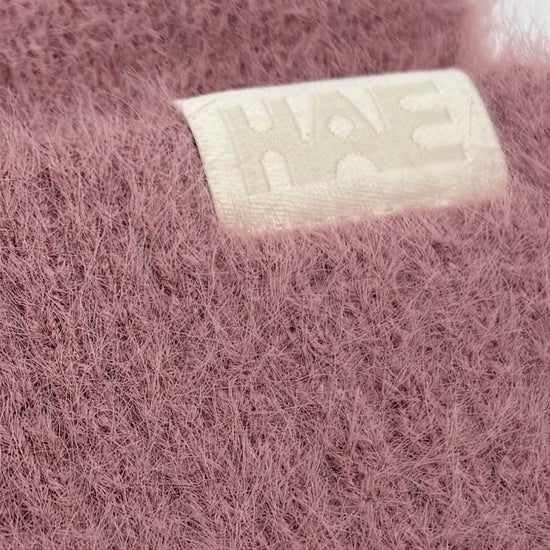 Adventurer 2.0 Mütze von HAE in Rosa – Detailaufnahme des HAE-Labels auf dem flauschigen Polyamid-Gewebe