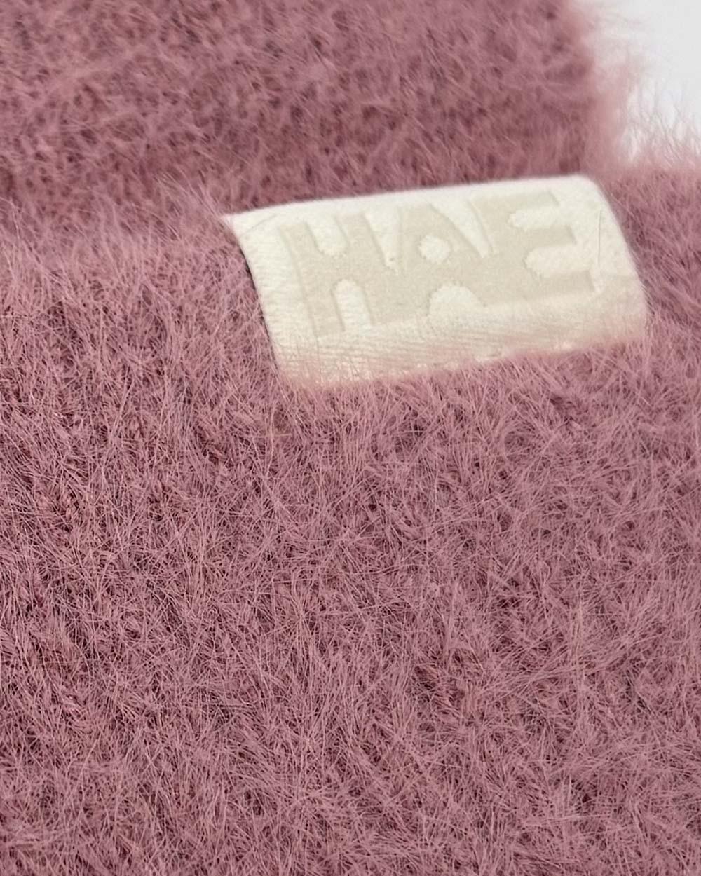 Adventurer 2.0 Mütze von HAE in Rosa – Detailaufnahme des HAE-Labels auf dem flauschigen Polyamid-Gewebe