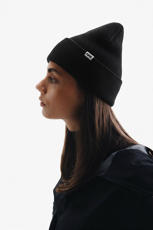 HAE Adventurer 2.0 Beanie in Schwarz am Model getragen, seitliche Ansicht mit HAE-Label am Bund