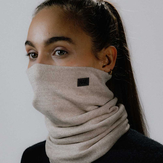 Das weibliche Model trägt den Merino Halsschlauch in Beige