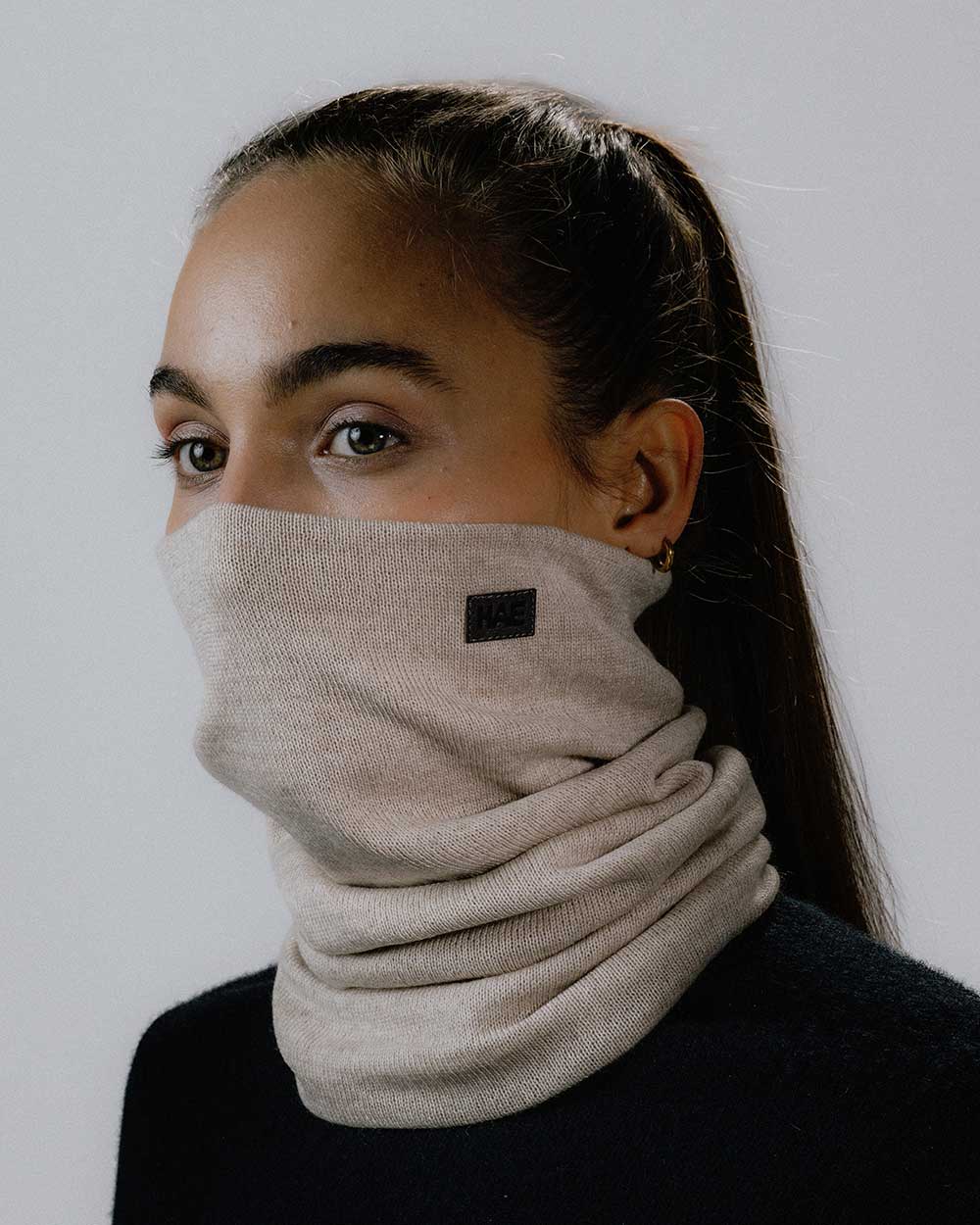 Das weibliche Model trägt den Merino Halsschlauch in Beige