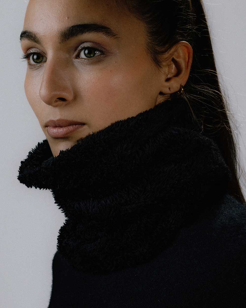 Das weibliche Model trägt den Wellness Neckwarmer in Schwarz