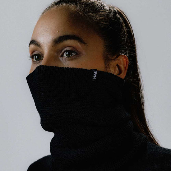 Das weibliche Model präsentiert den Neckwarmer in Schwarz